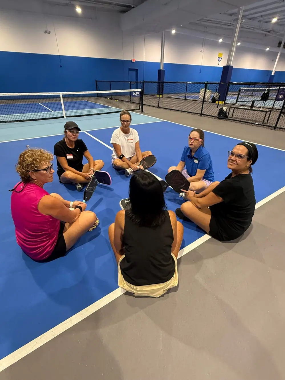 A Pickle and Prayer group seated in a circle on the court for the devotion