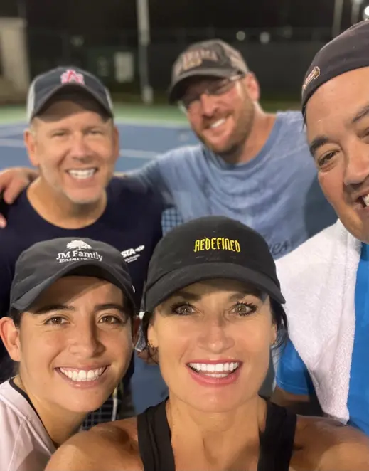 Dr. Sonya Rogers and four players smiling together on the court after a game